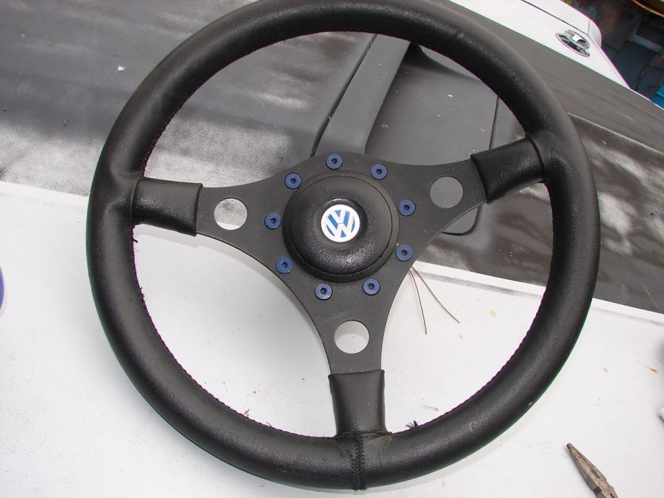 Black aftermarket steering wheel with VW logo