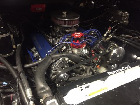 1982 Ford Bronco - A close-up view of a modified V8 engine bay, featuring a blue "RACING" branded valve cover, a red MSD ignition distributor, and a chrome ai…