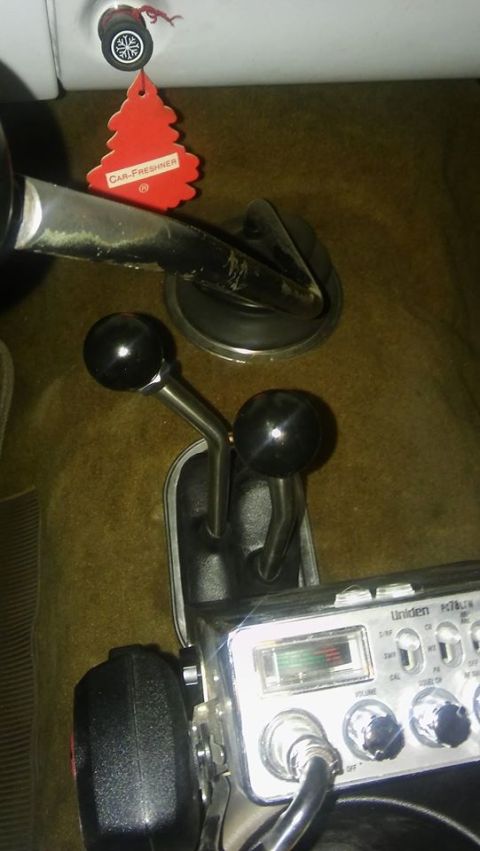1979 Ford Bronco - The interior of a vehicle shows a CB radio and two gear shift levers. A red car freshener hangs from a knob above the levers.
