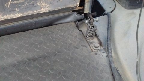 1985 Ford Bronco - The latch mechanism for a vehicle's cargo area features a coiled spring and metal components.