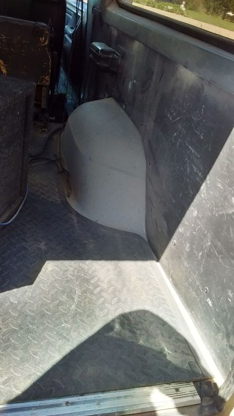 1985 Ford Bronco - Interior view of a vehicle's cargo area with diamond plate flooring and gray plastic panels.