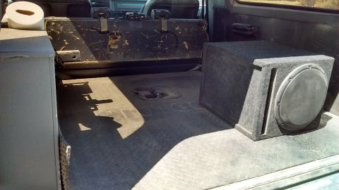 1985 Ford Bronco - The cargo area of a 1985 Ford Bronco shows a subwoofer box and a roll of paper towels on the left side.