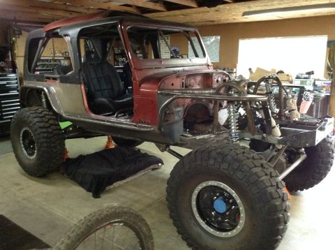 1985 Jeep CJ7 - A custom-built Jeep CJ7 is shown in a garage, undergoing modifications with a roll cage, large off-road tires, and exposed suspension compo…