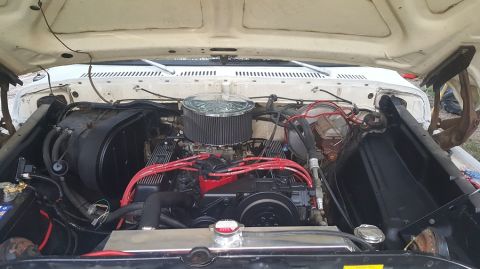 1978 Ford Bronco - The engine bay of a classic Ford truck is shown with the hood open. A large chrome air cleaner sits atop the carburetor, with red spark plu…