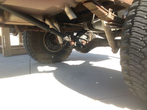 1979 Ford Bronco - The underside of a vintage Ford Bronco shows the rear axle, leaf springs, shock absorber, and driveshaft. The vehicle is parked on a concre…