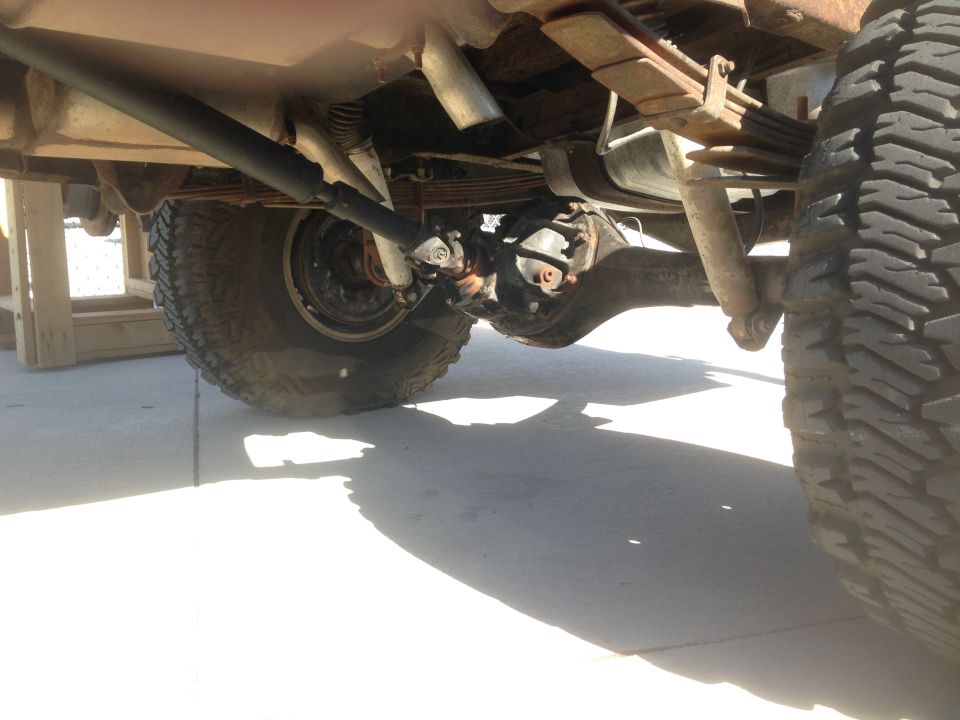 Underside of a vintage Ford Bronco showing rear axle, leaf springs, shock, and driveshaft.