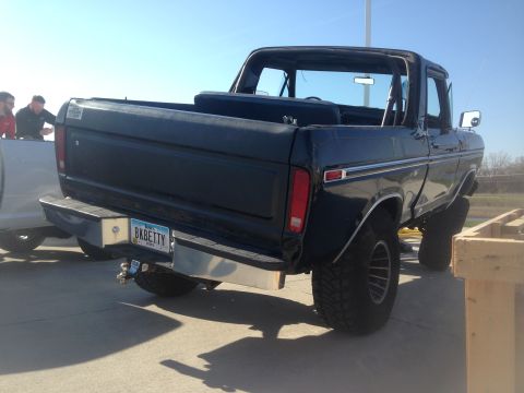 1979 Ford Bronco - The rear driver's side view of a lifted, dark-colored 1979 Ford Bronco is shown with a custom license plate that reads "BKBETTY". The vehic…