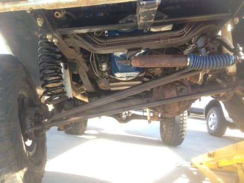 1979 Ford Bronco - The underside of a vintage Ford Bronco shows its suspension system, including a large coil spring, shock absorber, and steering linkage. Th…