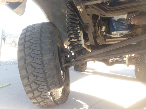 1979 Ford Bronco - Low angle view of the front suspension and tire of a lifted Ford Bronco. The image shows the coil spring, shock absorber, and part of the d…