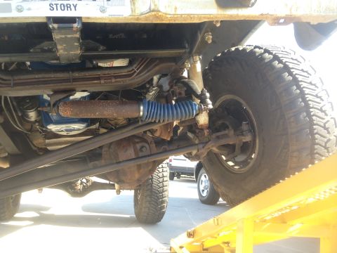 1979 Ford Bronco - Underside view of a heavily modified 4x4 vehicle, likely a truck or SUV, showing the front suspension, steering components, and large off-r…