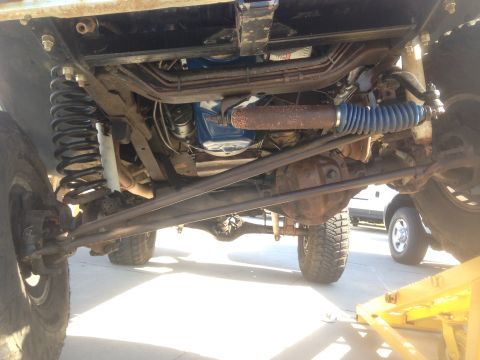 1979 Ford Bronco - Underside view of a lifted 4x4 vehicle's suspension and steering components, featuring large coil springs, shocks, and heavy-duty tie rods.…