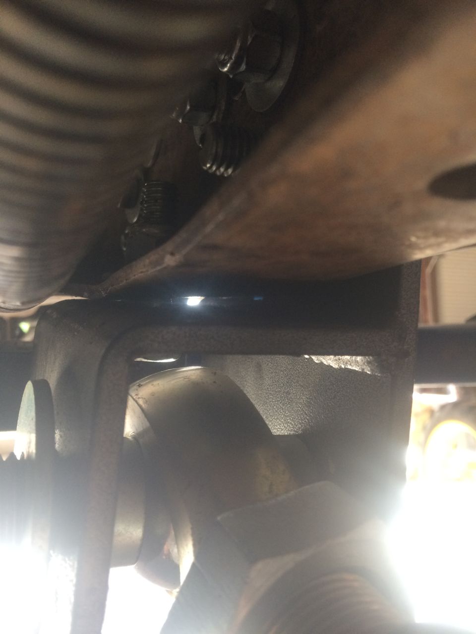 Close-up of rusty vehicle undercarriage components with bolts and brackets.