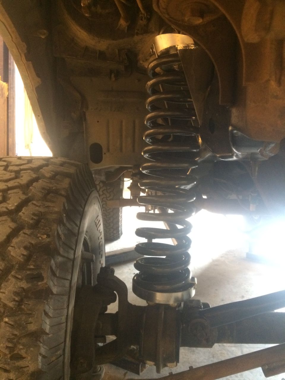 Close-up of vehicle front suspension and coil spring.