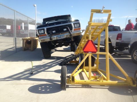1979 Ford Bronco - A lifted black 1979 Ford Bronco, nicknamed "Black Betty" on its license plate, is parked outdoors next to a yellow trailer with a red trian…