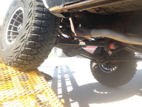 1979 Ford Bronco - The underside of a lifted vehicle, likely a 1979 Ford Bronco, is shown with a large off-road tire on the left and the rear axle and suspens…