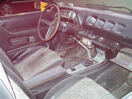 Interior of a classic car showing driver's seat, dashboard, and shifter.