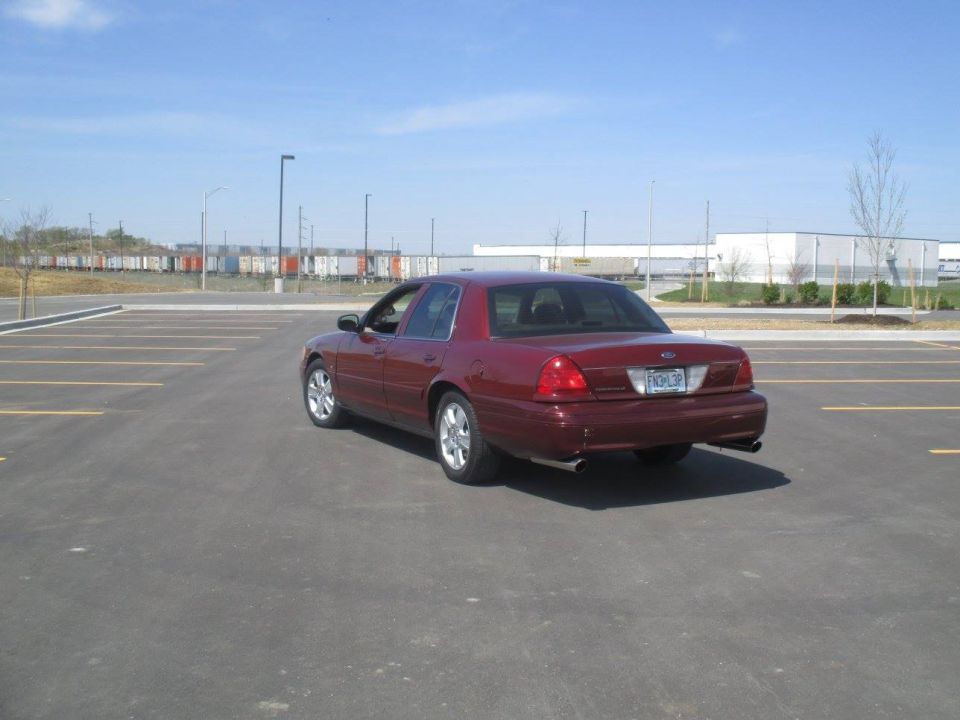 Dark red 2004 Ford Crown Victoria rear passenger side view in a parking lot.