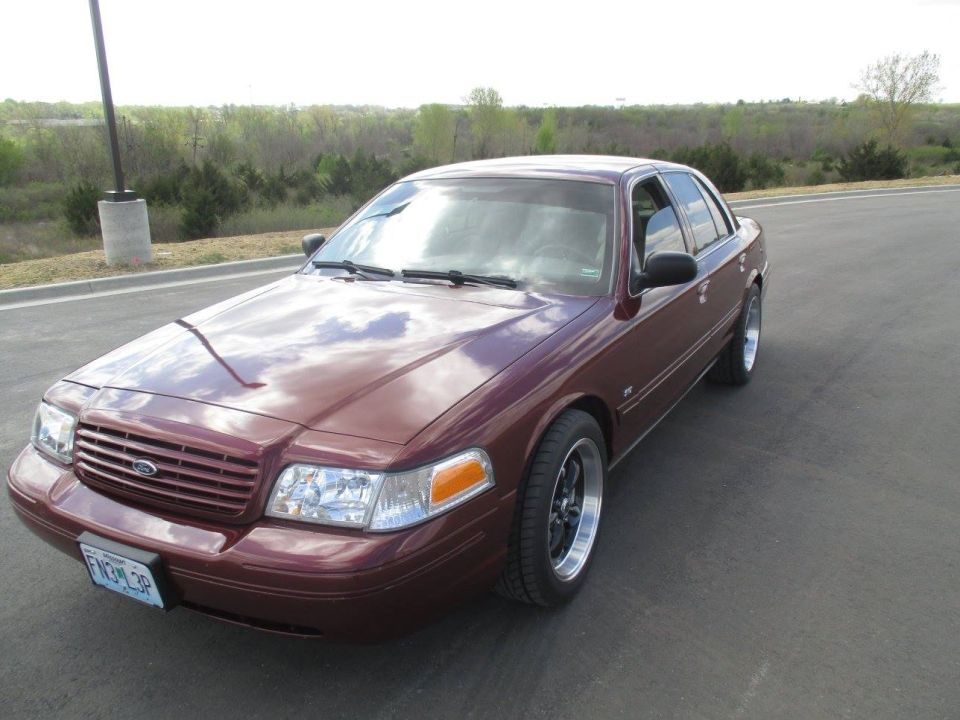 Maroon 2004 Ford Crown Victoria with custom wheels, parked on asphalt.
