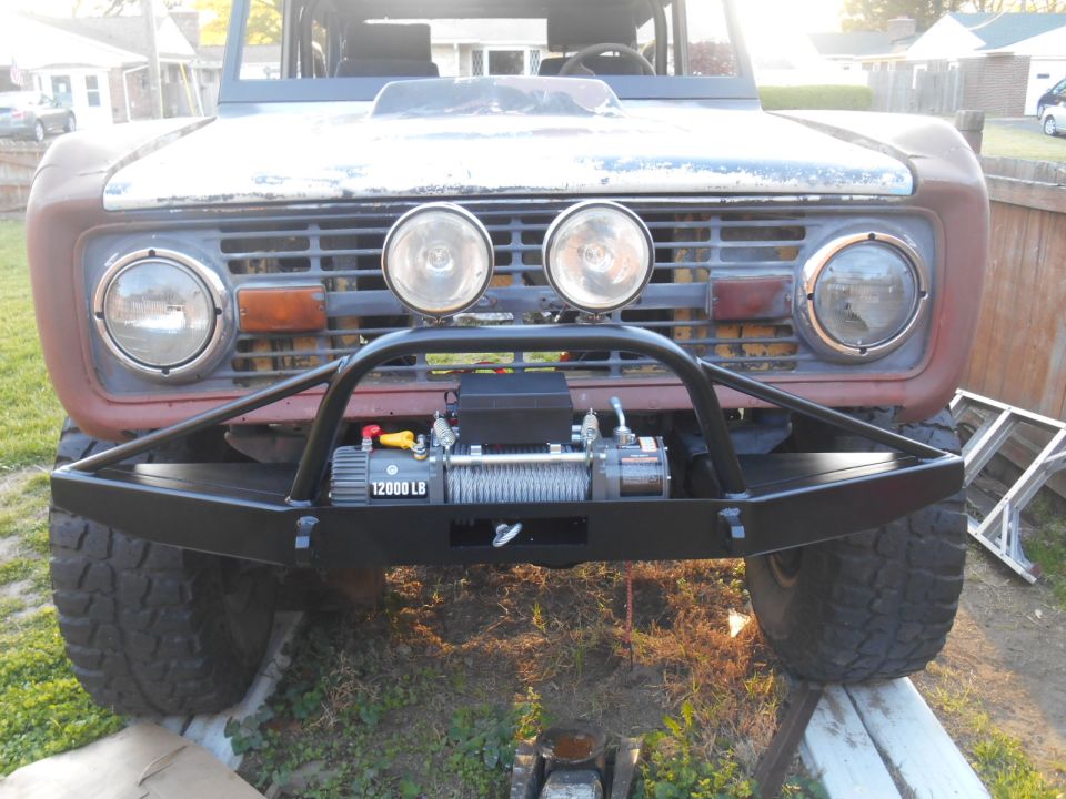 Weathered Ford Bronco front with black bumper, winch, and round headlights.