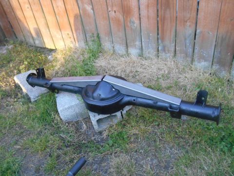 1972 Ford Bronco - A black Ford 9-inch rear end assembly is supported by concrete blocks on a grassy area in front of a wooden fence.