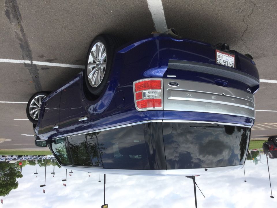 Dark blue SUV, rear passenger side, silver tailgate trim with XLE and Ford logo.
