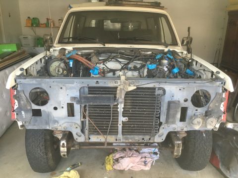 1987 Ford Bronco - Front view of a white Ford Bronco with its hood open and the grille and front bumper removed, revealing the engine and radiator. The vehicl…