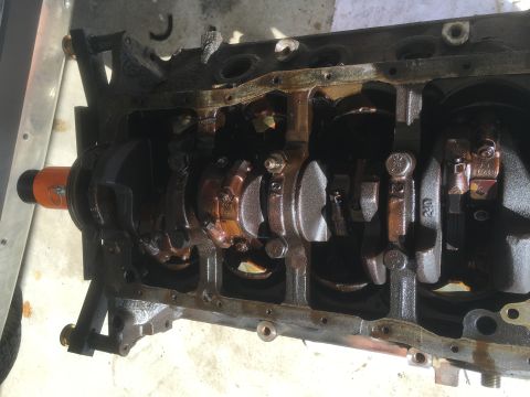 1987 Ford Bronco - The inside of a disassembled engine block is shown, with the crankshaft and connecting rods visible. The engine appears to be covered in oi…