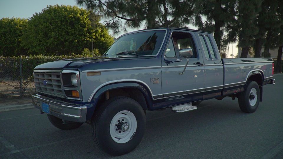 1980s Ford F-Series pickup truck, blue and grey two-tone paint, parked outdoors.