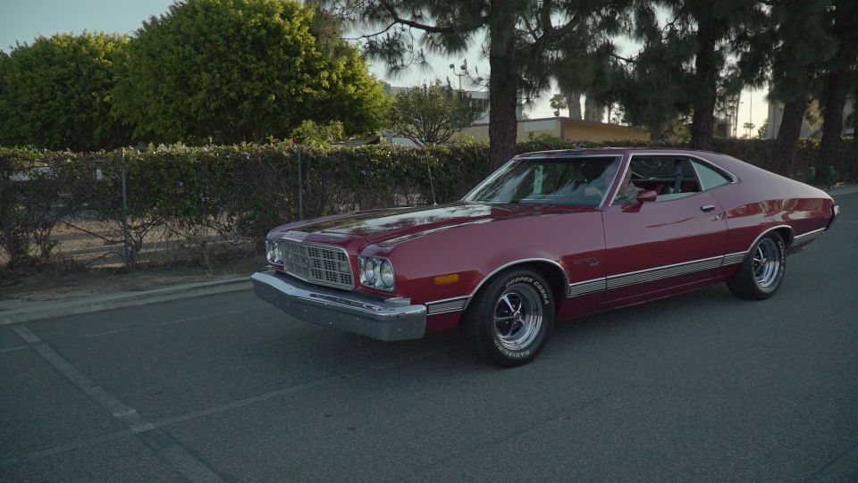 Maroon 1970s Ford Gran Torino coupe, 3/4 front view, parked on asphalt.