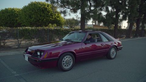 1993 Ford Taurus - A maroon sedan is parked on the side of the road with trees in the background.