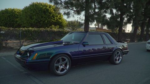 1993 Ford Taurus - A modified Ford Mustang with a distinctive hood scoop and multi-tone paint sits parked on a street.