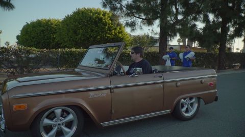 1993 Ford Taurus - A brown 1970s Ford Bronco convertible with custom wheels and lowered suspension is seen from the side.