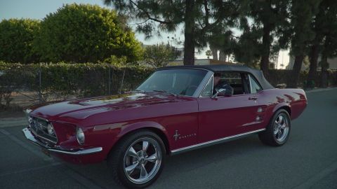 1993 Ford Taurus - A classic maroon Ford Mustang convertible is parked on a street with trees in the background.