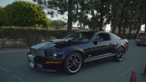 1993 Ford Taurus - Black Ford Mustang Shelby GT with racing stripes is seen at a car show.