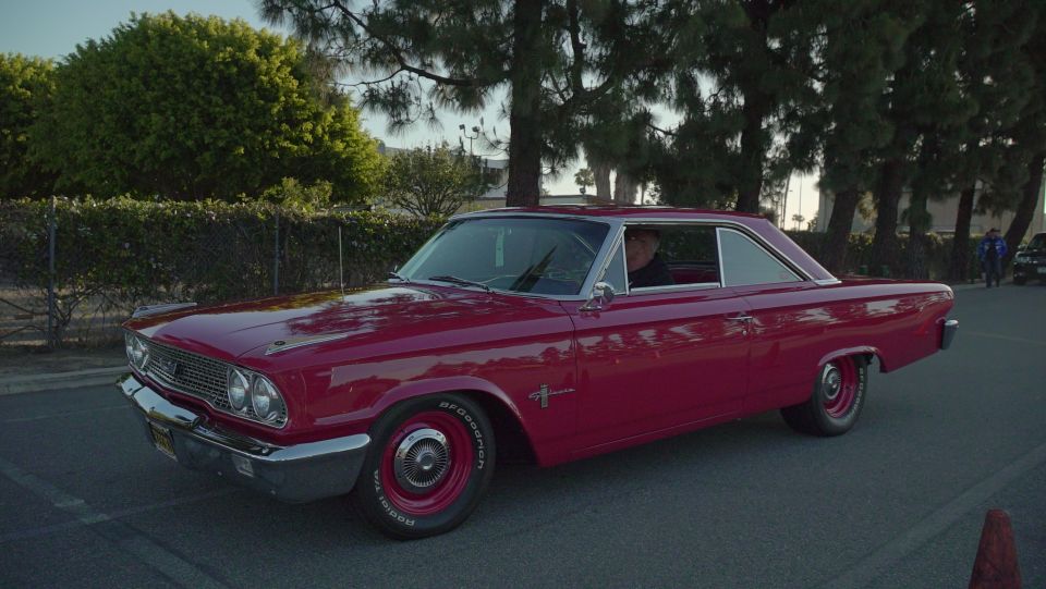 Red 1963 Ford Galaxie coupe parked outside with trees in background