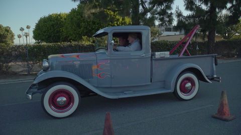 1993 Ford Taurus - A classic gray pickup truck with flame decals and white wall tires drives down a street.