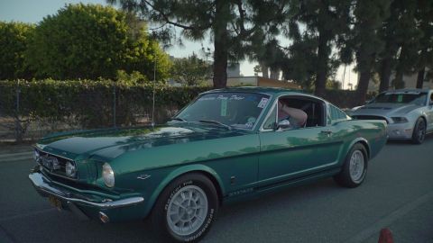 1993 Ford Taurus - A green 1965 Ford Mustang Fastback is seen from the side, with another Mustang following behind.