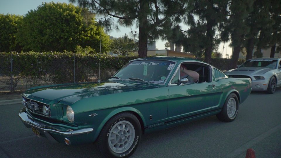 Green 1965 Ford Mustang Fastback side view with a silver Mustang behind it