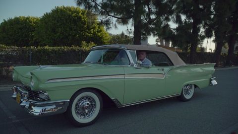 1993 Ford Taurus - A man drives a classic light green 1957 Ford Fairlane convertible down a suburban street.