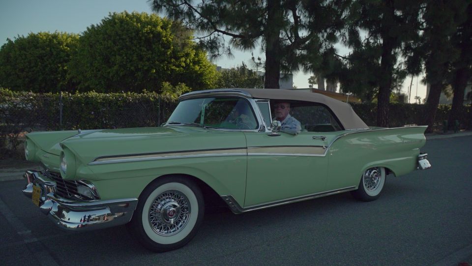Light green 1957 Ford Fairlane convertible with a tan top, chrome trim, and wire wheels
