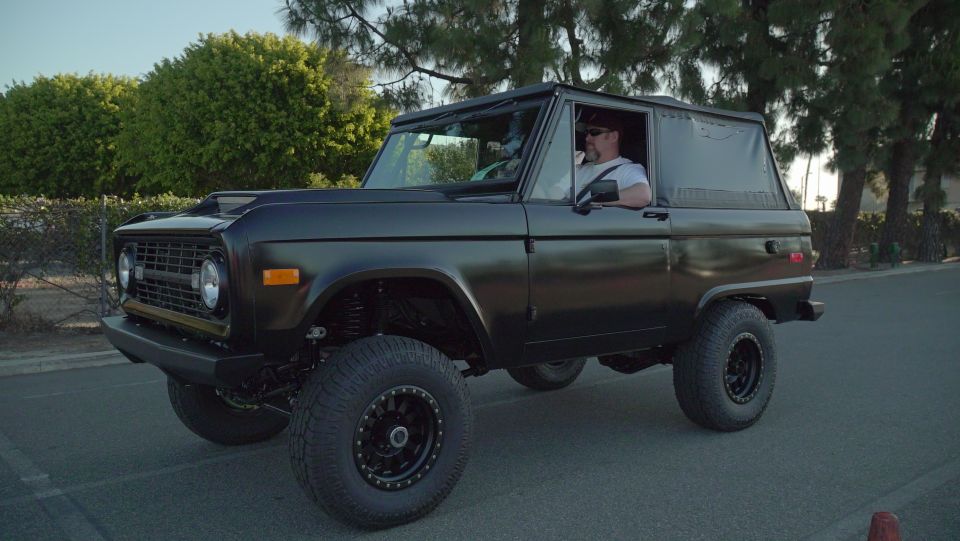 Black 1970 Ford Bronco with lifted suspension and off-road tires, seen from a 3/4 front angle