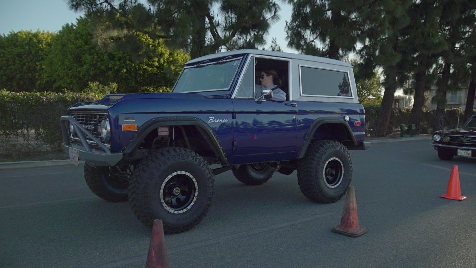 Blue 1975 Ford Bronco with lifted suspension and off-road tires, side view