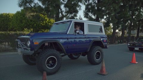 1993 Ford Taurus - Modified 1975 Ford Bronco with lifted suspension and off-road tires is seen driving on a street.