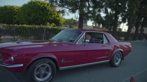 1993 Ford Taurus - Side view of a red 1967 Ford Mustang coupe with a driver visible.