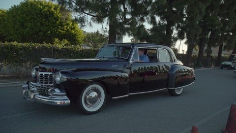 1993 Ford Taurus - A driver is visible inside the classic black Lincoln Continental as it cruises down the street.