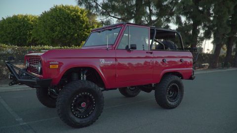 1993 Ford Taurus - This red Ford Bronco, likely from the mid-1970s, features significant off-road modifications including a custom bumper and large tires.