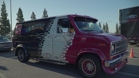 1993 Ford Taurus - A customized van, painted with flames and text, is parked next to a Ford Performance trailer.