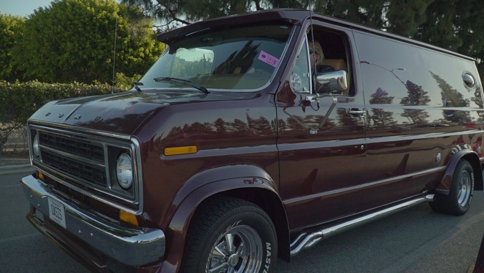 Maroon custom van with chrome side pipes and a visor, parked outdoors