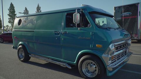 1993 Ford Taurus - A vintage teal van with custom details is parked at an outdoor event, with other vehicles and a trailer visible in the background.
