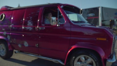 1993 Ford Taurus - A customized purple van with floral graphics and chrome side pipes is seen from the side, with another vehicle in the background.